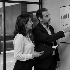 Gestores hoteleiros analisam um painel de indicadores mensais enquanto a operação do hotel acontece ao fundo.