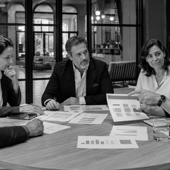 Equipe de gestores hoteleiros analisa informações e debate diferentes perspectivas antes de tomar uma decisão.