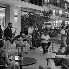Conjunto musical se apresenta para hóspedes no lounge integrado à piscina de um hotel.